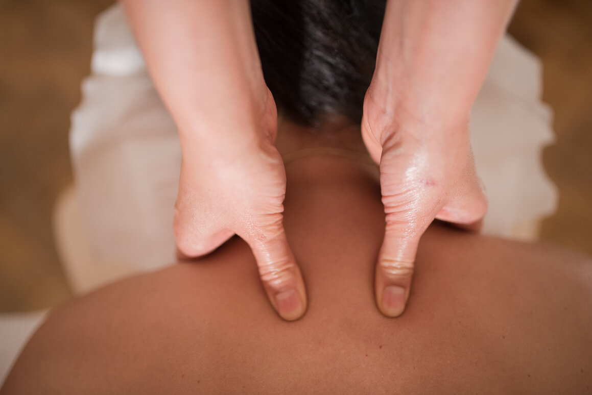 Therapist applying deep tissue pressure to a client’s upper back