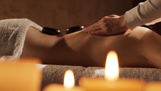 Massage therapist preparing a treatment couch with fresh towels and oils